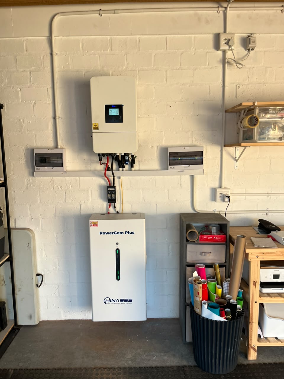 Sun Savings inverters and a distribution board mounted on a plant room wall